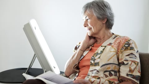 Older white woman using a seasonal therapy light