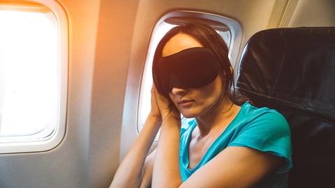 Woman with a sleep mask resting on a plane