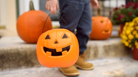 Child holds a pumpkin bucket for trick-or-treating