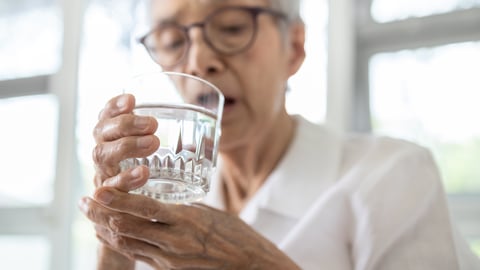Older women having difficulty lifting a glass of water