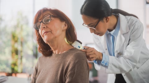 older white woman getting exam for melanoma by Asian female doctor