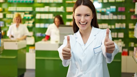 Laughing pharmacist in pharmacy holds both thumbs up; Shutterstock ID 1840950766