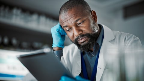 Scientist man, stress and technology for medical research in a laboratory with slow internet. Science person or doctor frustrated at desk with fatigue, burnout and mental health working on tablet; Shutterstock ID 2257442121