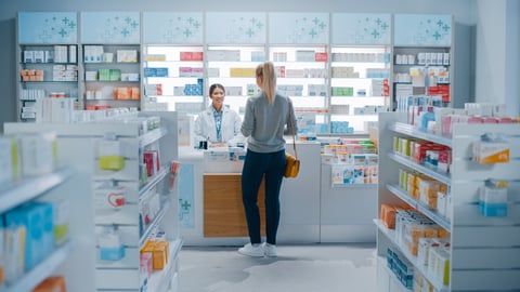 Pharmacy Drugstore: Beautiful Young Woman Buying Medicine, Drugs, Vitamins Stands next to Checkout Counter. Female Cashier in White Coat Serves Customer. Shelves with Health Care Products; Shutterstock ID 1952231947