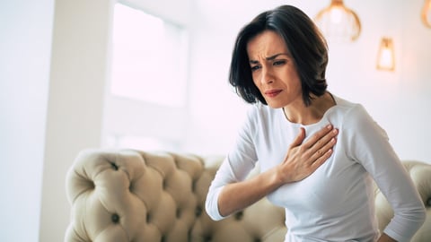 Pressure in the chest. Close-up photo of a stressed woman who is suffering from a chest pain and touching her heart area.; Shutterstock ID 1712713267