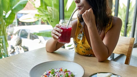 Candid lifestyle portrait of beautiful brunette ethnic woman drinking juice eating organic plant-based cauliflower dish for vegetarians or vegans; Shutterstock ID 1506045989