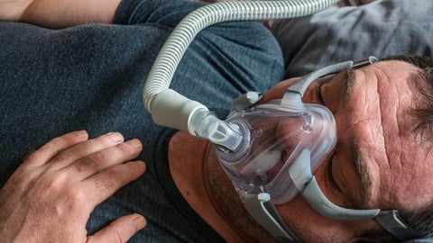 A man in an oxygen mask for CPAP therapy in bed; Shutterstock ID 1675350667