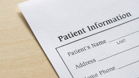 Closeup of a blank patient information form isolated on a wooden background.; Shutterstock ID 2130160823