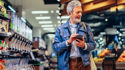 Senior man is doing grocery shopping, holding mobile phone with a shopping list and having shopping bag on his shoulder; Shutterstock ID 2149431149