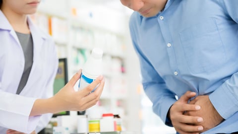 Male patient having stomach pain, consulting with pharmacist in pharmacy; Shutterstock ID 683162431