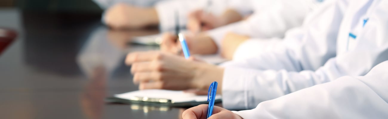 people in white coats taking notes at a meeting