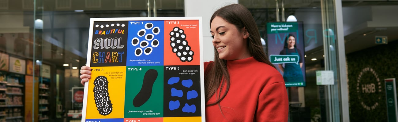 Artist Coco Lom holds up her poster outside a store.