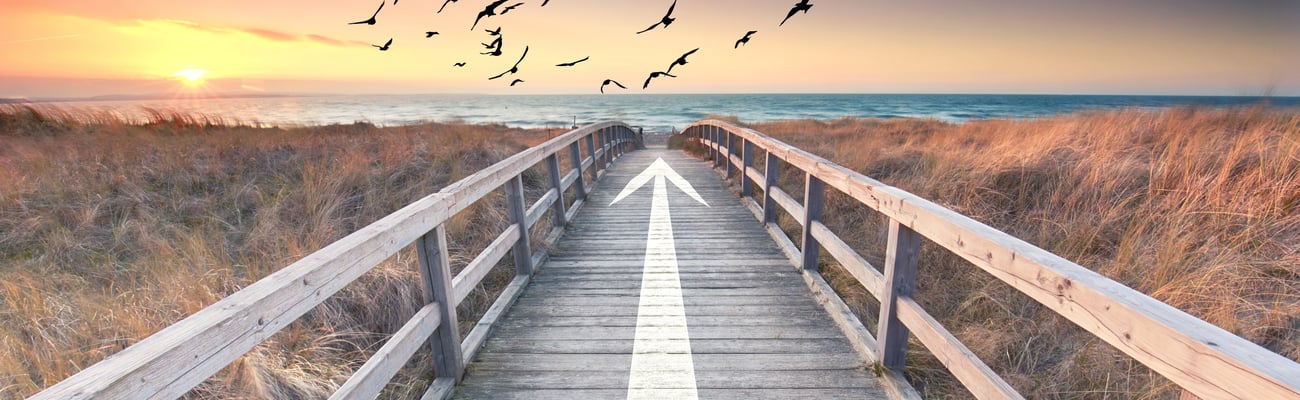 boardwalk at sunset with an arrow pointing to the beach