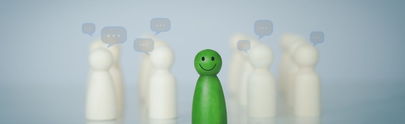 One green wooden figure among white ones