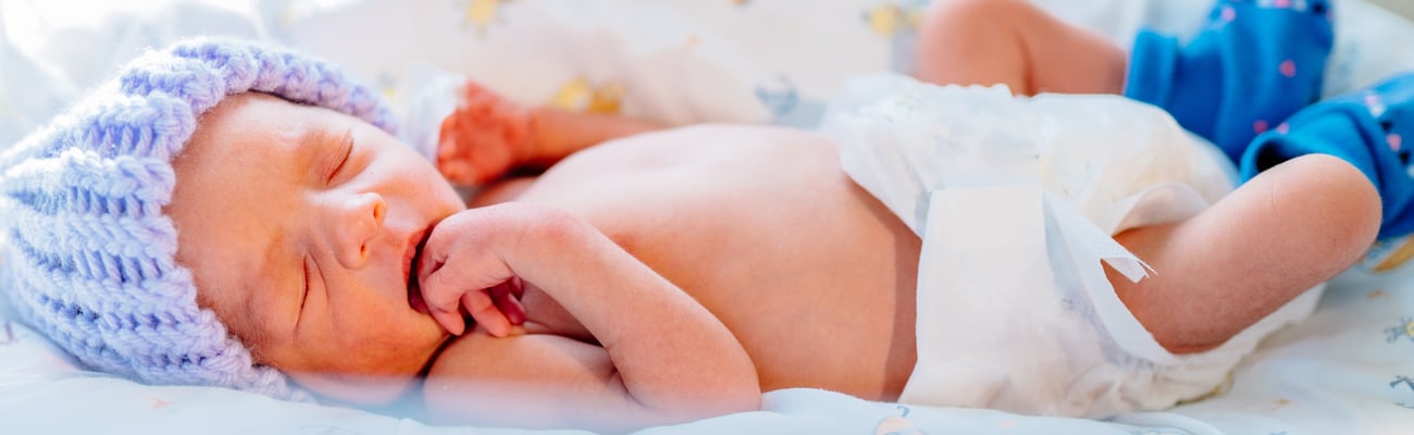 premature baby birth in hospital bed wearing a cap and booties