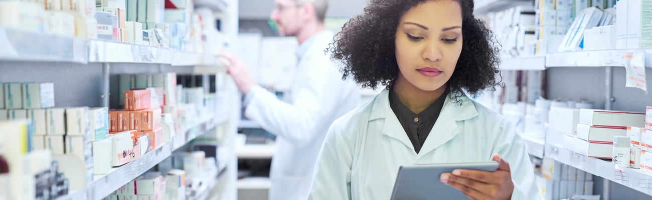 Young pharmacist examining a box of pills