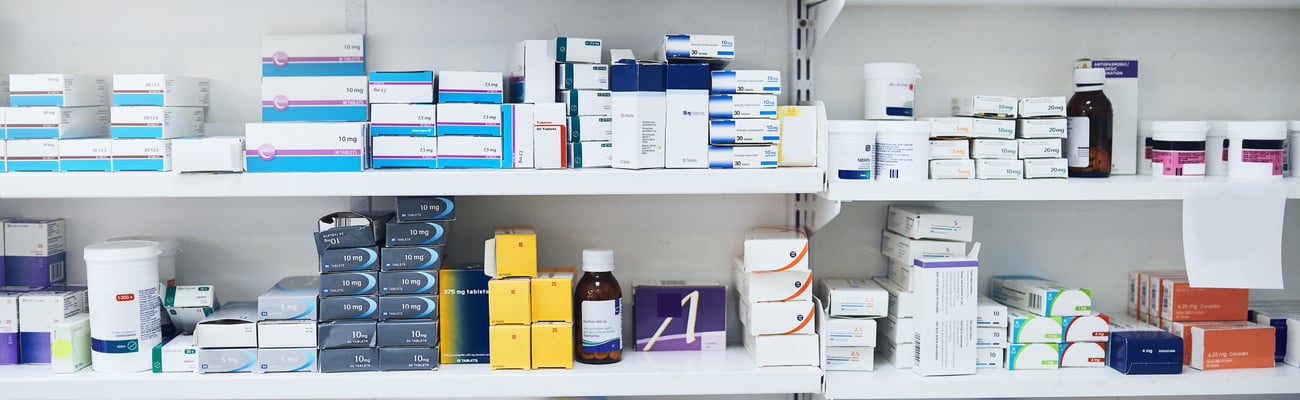 Shelf in a pharmacy full of boxes and bottles of drugs