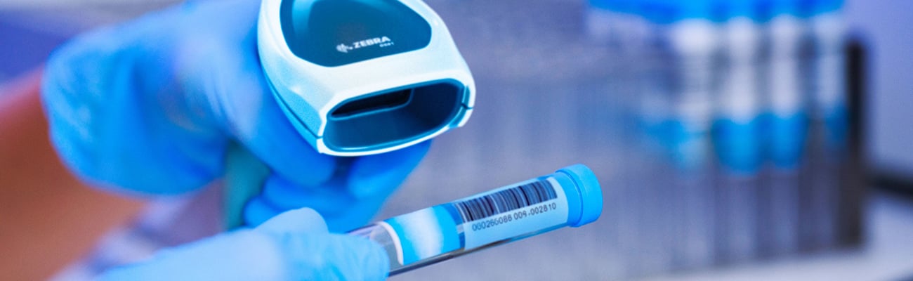 Gloved hand scans barcode on test tube.