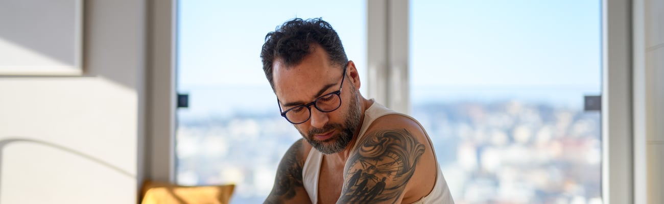 Tatooed white man checking his blood sugar with a continuous glucose monitor