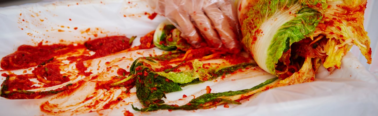 Close up of a cook's hand preparing kimchi