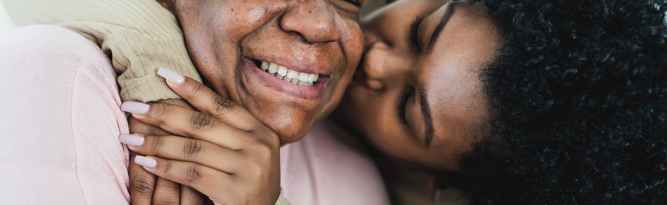 Adult daughter giving her older mother a hug and kiss