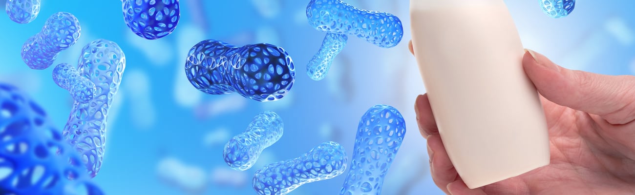 blue probiotics closeup with pill bottle in the foreground, held by white hand