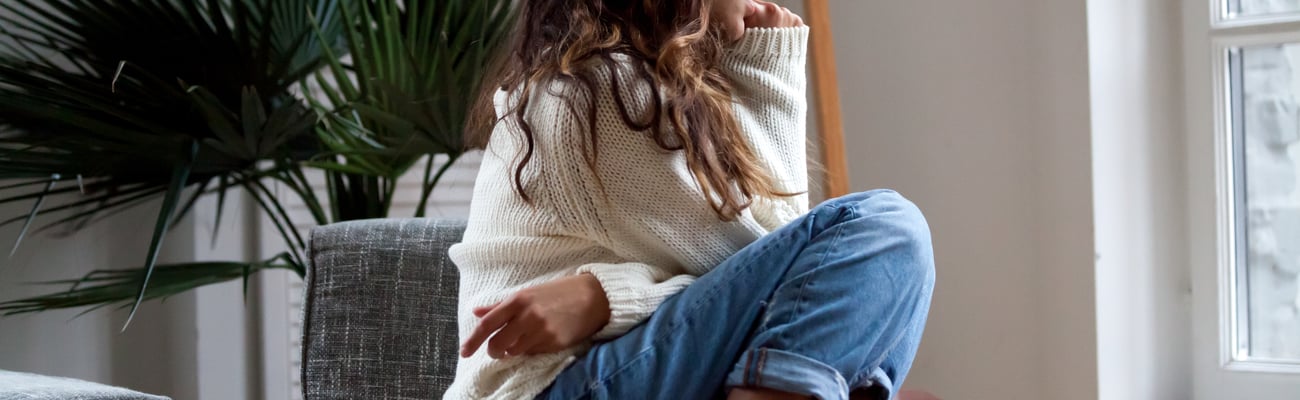 Teen girl sitting.curled up in a chair looking anxious