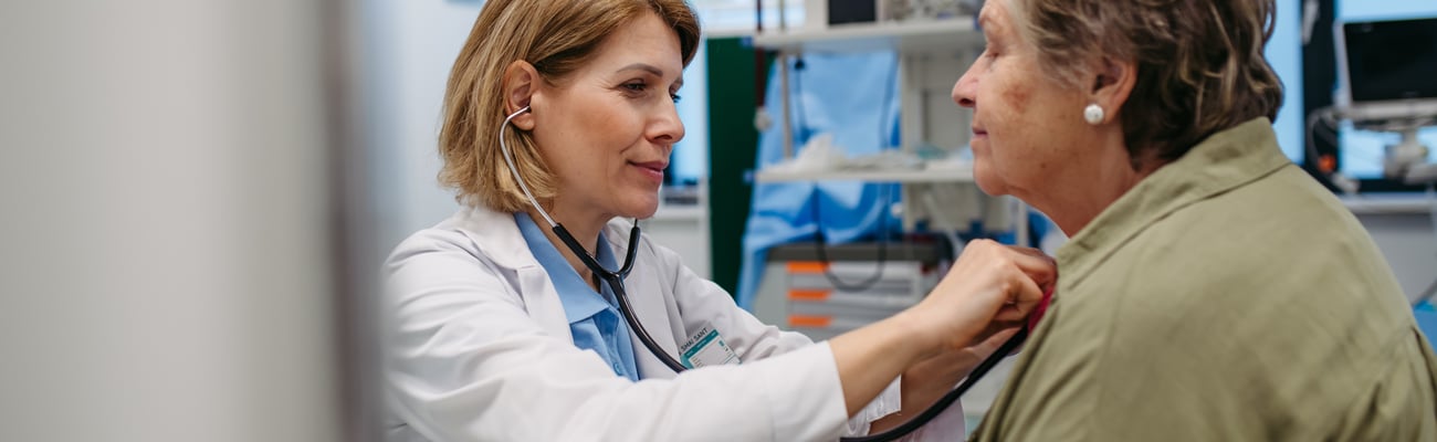 Woman doctor listening to the heartbeat of an older woman patient