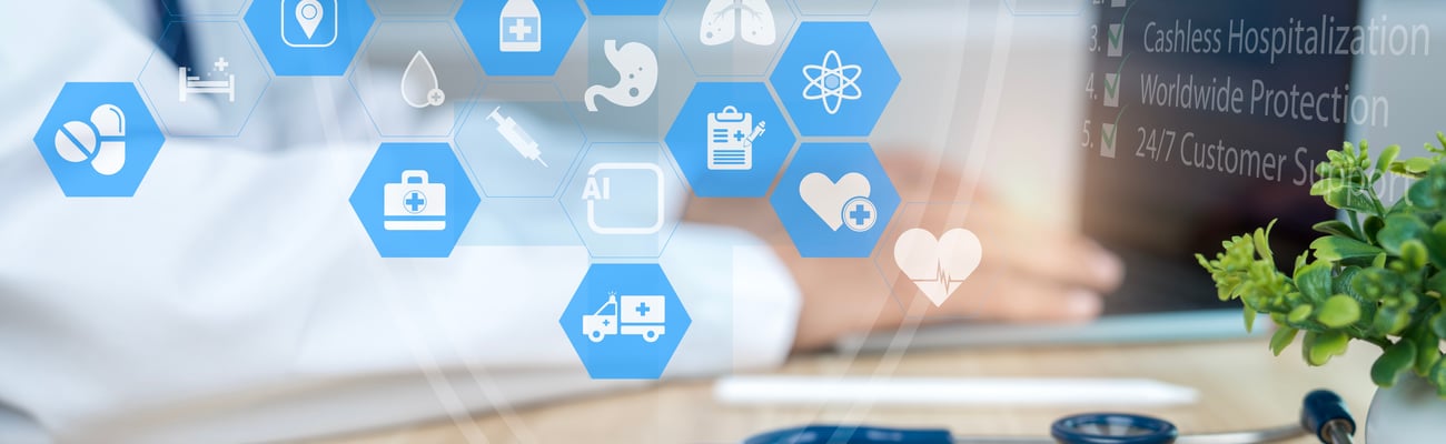 Stethoscope in the foreground while a doctor works on a laptop