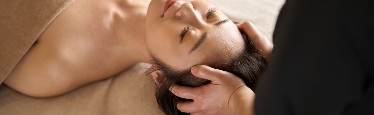 A woman receives a head massage at a spa.