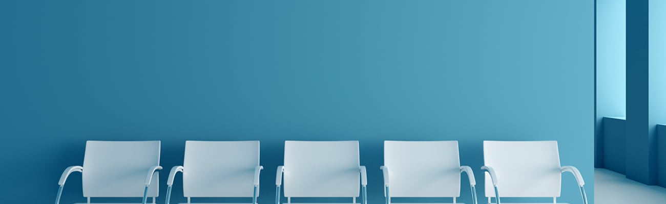 A set of white empty chairs in a clinic waiting room