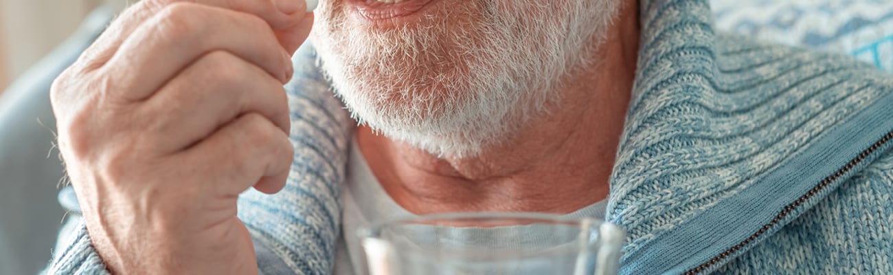 Older fair-skinned man taking a pill
