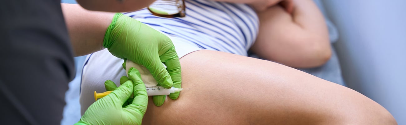 Nurse injecting medicine into a patient's upper thigh