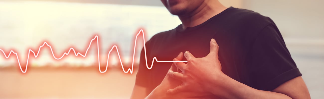 Chest of man holding left side of chest with cardiogram image in background