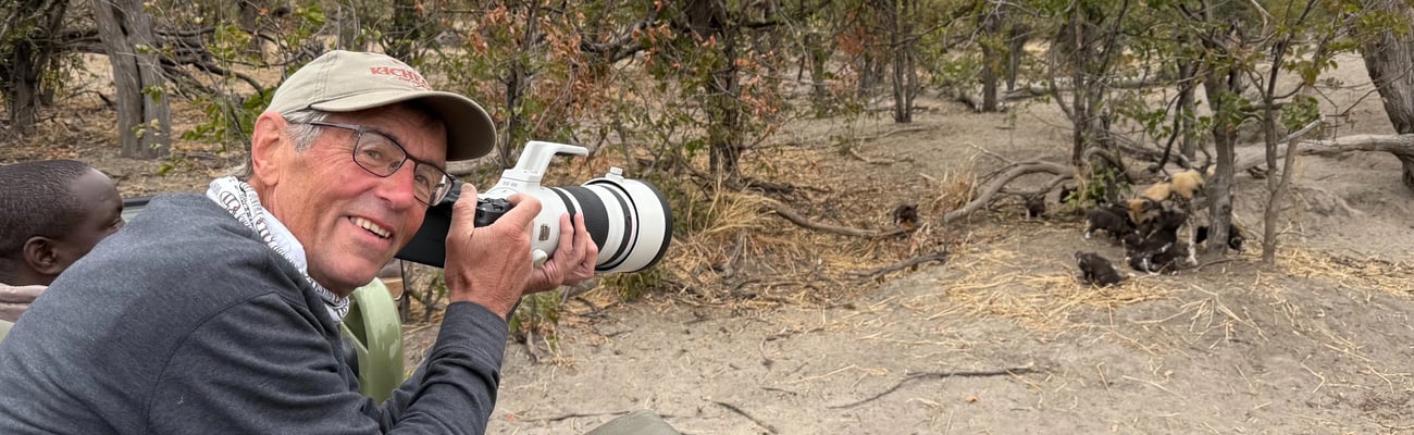 Dr. Don Gutoski holds a camera in front of wildlife.