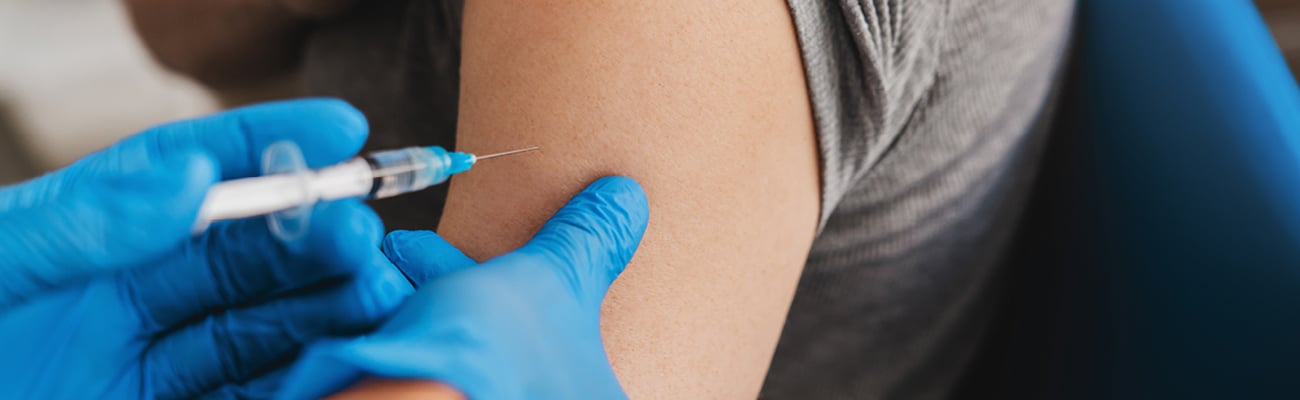 Close up of an arm with a rolled up sleeve about to get a vaccine