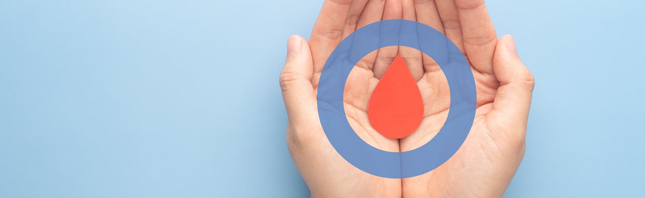 A pair of hands holding a symbol for a drop of blood
