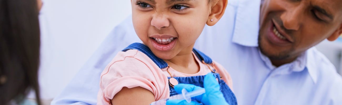 Cute little girl scrunching her face in anxiety about to get a vaccine