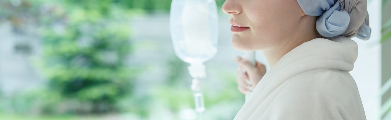 Young woman with skin cancer standing on a drip in hospital; Shutterstock ID 704925163
