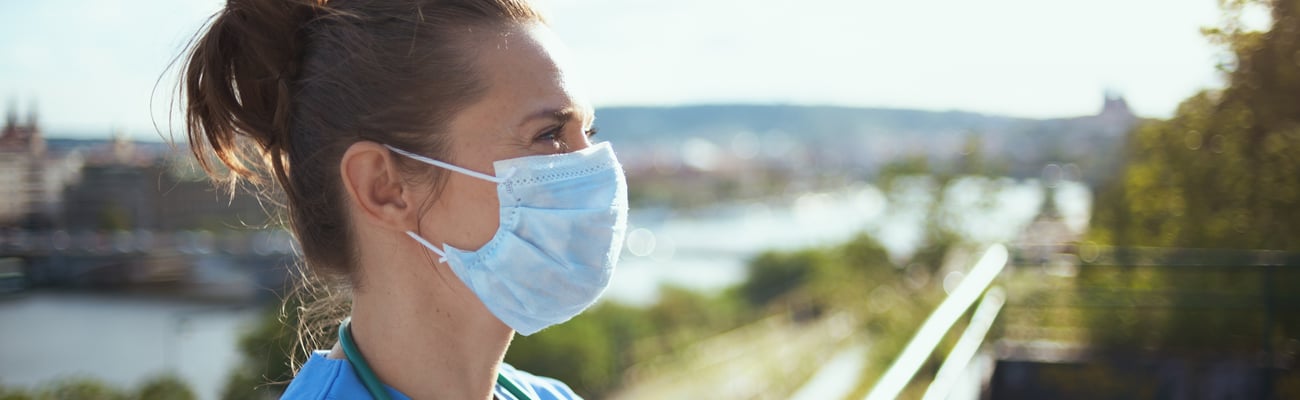 Woman doctor with a mask standing in front of a fence