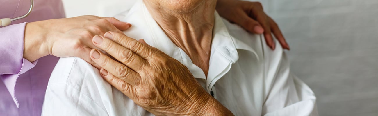 An senior citizen holding a healthcare worker's hand