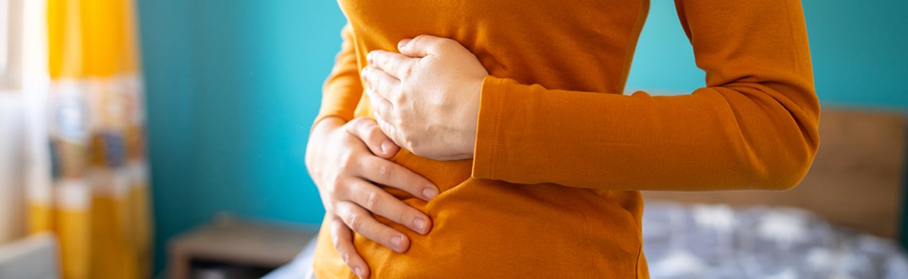A young woman holding her stomach to indicate discomfort due to IBS