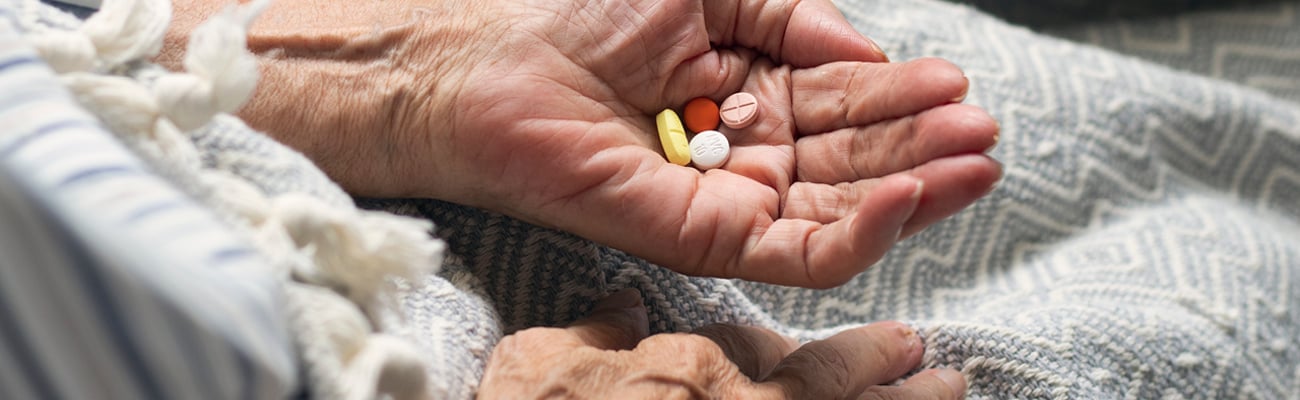 Senior woman's hand holding pills to indicate a potential problem with polypharmacy