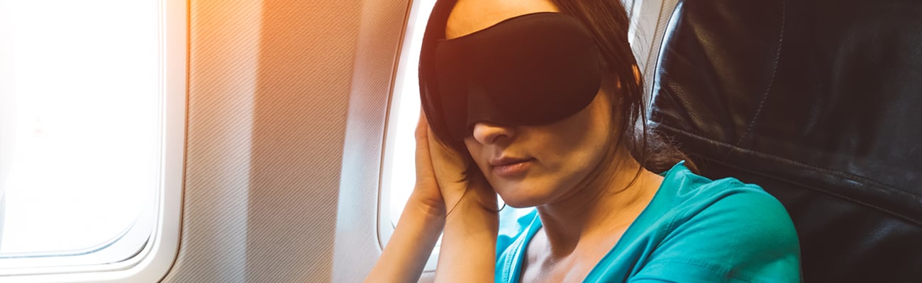 Woman with a sleep mask resting on a plane