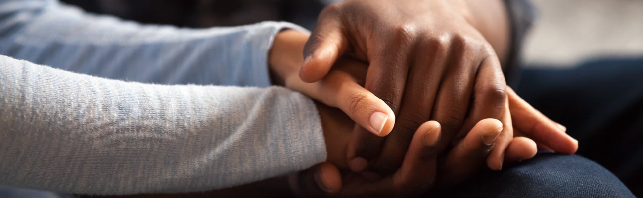 Close up of young people holding hands to comfort each other in a difficult situation