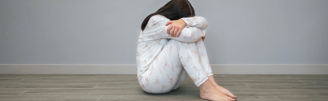 woman in pyjamas on floor hiding face