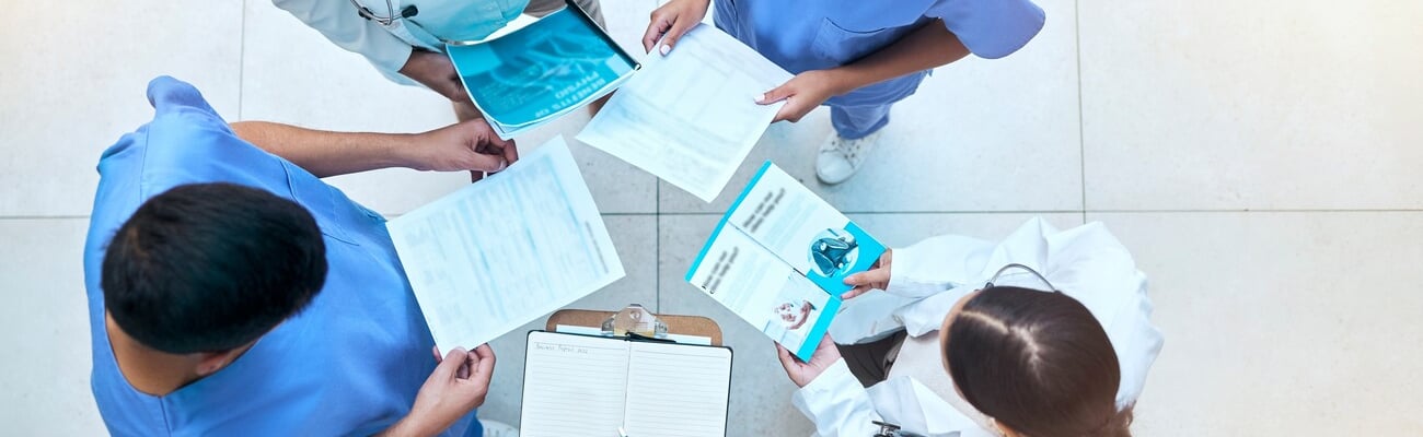 Doctor, team and documents in collaboration above in healthcare planning, meeting or brainstorming at hospital. Group of medical professionals with paperwork in teamwork, strategy or ideas at clinic; Shutterstock ID 2282908649