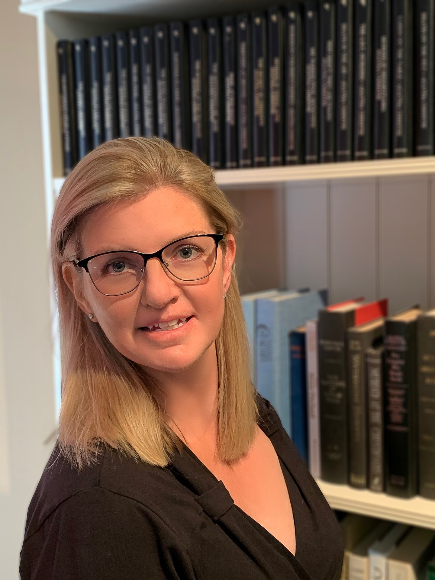 a woman wearing glasses and smiling at the camera