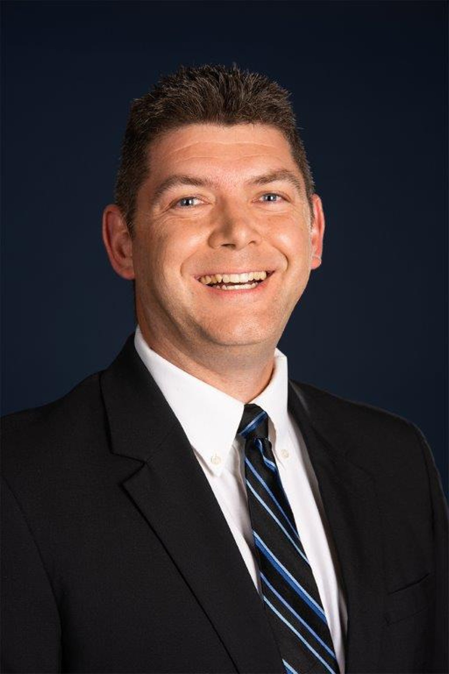 a man wearing a suit and tie smiling at the camera