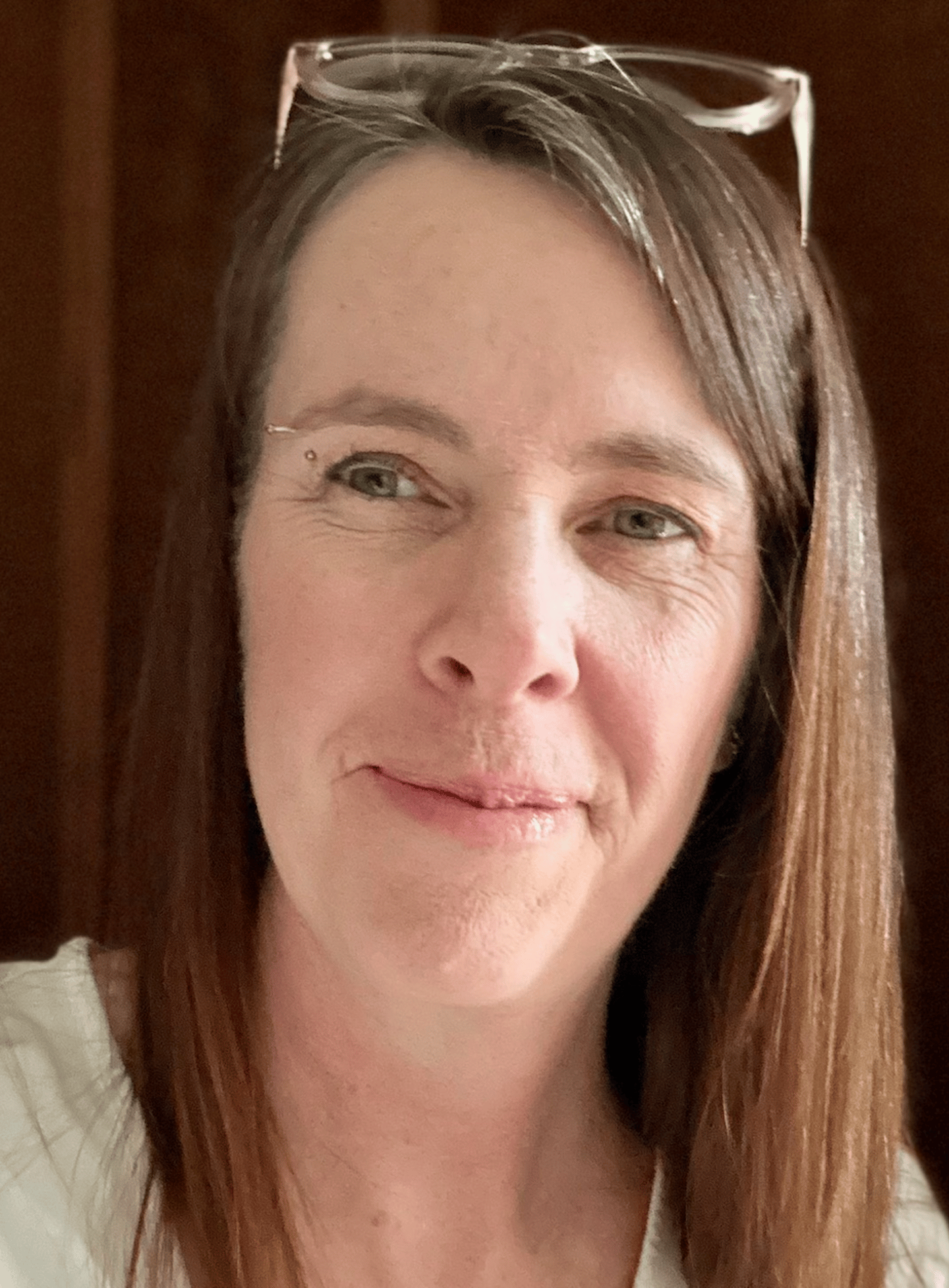 White woman with brown hair and glasses pushed back on top of her head